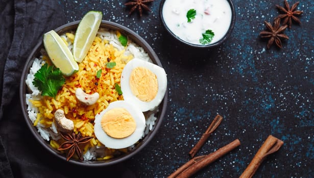 Indian Egg Biryani or anda rice top view on dark background. Egg Biryani - Basmati rice cooked with masala roasted eggs and spices, served with yogurt. Copy space for text