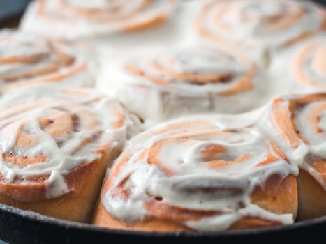 Idea and recipe pastries - perfect cinnamon rolls with topping in skillet. Close up view of vegan swedish cinnamon buns Kanelbullar with pumpkin spice,topping vegan cream cheese. Copy space for text