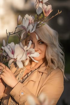 Magnolia flowers woman. A woman is holding a magnolia flower in her hand and standing in front of a tree. Concept of serenity and beauty, as the woman is surrounded by nature and the flower adds a touch of color