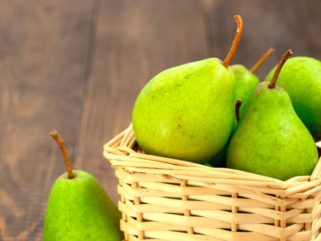 Healthy organic pears in basket on dark wooden background with copy space