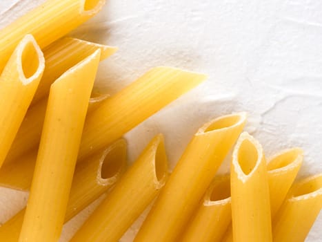 Raw pasta as food background. Italian Penne Rigate Macaroni Pasta on textured white background. Dried pasta selection close up. Top view or flat lay with copy space