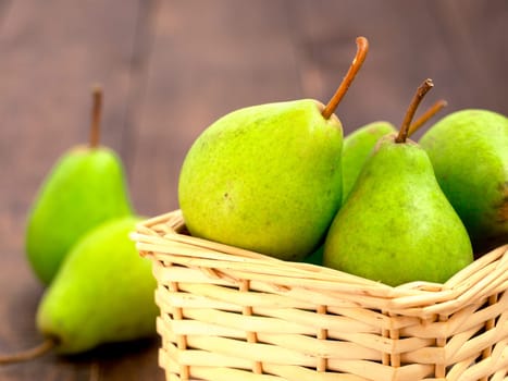 Healthy organic pears in basket on dark wooden background with copy space