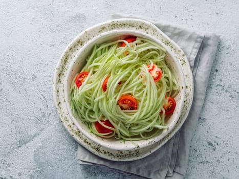 Zucchini noodles salad with cherry tomatoes. Vegetable noodles - green zoodles or courgette spaghetti salad ready-to-eat. Clean eating, raw vegetarian food concept. Copy space. Top view or flat lay.
