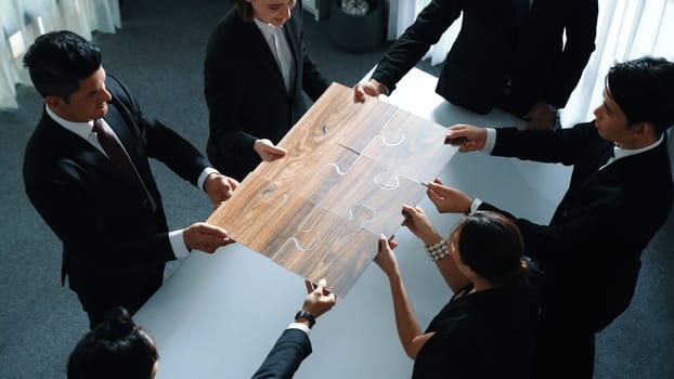 Top view of business people putting jigsaw together at meeting room. Professional marketing team standing at table while gathering puzzle piece. Show unity, cooperation and team working. Directorate.