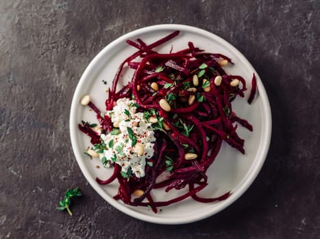 Raw beetroot spaghetti salad with soft cheese,nuts,thyme.Vegetable noodles - Fresh Beetroot Noodles with Ricotta and fresh thyme on plate. Copy space.Clean eating, raw vegetarian food concept.Top view