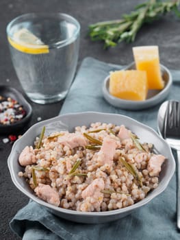 Raw buckwheat risotto with chicken meat and rosemary served parmesan cheese in gray plate on black cement background. Gluten-free and buckwheat recipe ideas. Copy space