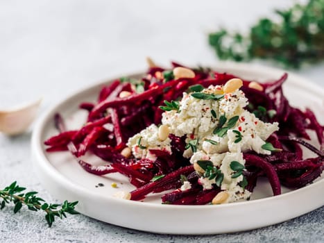 Raw beetroot spaghetti salad with soft cheese, nuts, thyme. Vegetable noodles - Fresh Beetroot Noodles with Ricotta and fresh thyme on plate. Copy space. Clean eating, raw vegetarian food concept