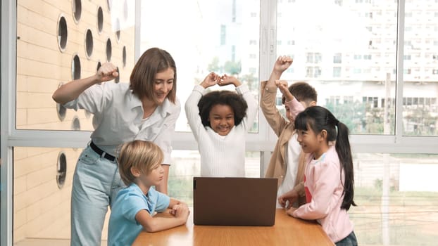 Group of diverse student and teacher celebrate successful project. Happy caucasian instructor looking at engineering code and cheering and encourage learner to improve skill at STEM class. Erudition.