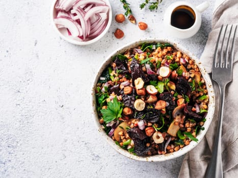 Warm buckwheat and beetroot salad on gray background. Vegetarian diet idea and recipe -salad with beetroot, buckwheat, mushrooms, onion, fresh herbs,hazelnut. Top view or flat-lay. Copy space for text