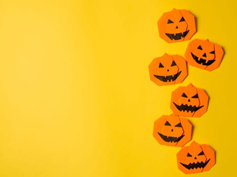 Halloween concept. Paper origami pumpkin on yellow background. Simple idea for halloween - easy made paper pumpkins on trendy color Ceylon Yellow background. Copy space for text.