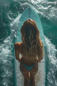 A young girl in a bikini is a surfer with a surfboard, floating on the waves.