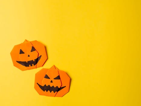 Halloween concept. Paper origami pumpkin on yellow background. Simple idea for halloween - easy made paper pumpkins on trendy color Ceylon Yellow background. Copy space for text.