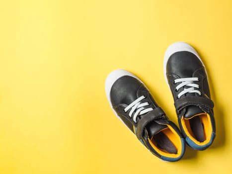 pair of new kids or adult sneakers on yellow background, top view. Flat lay gray and yellow or mustard color sneakers shoes on colorful bright background with copy space for text or design