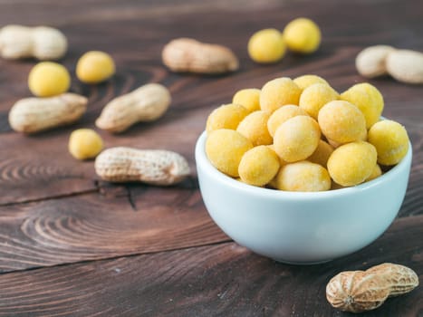 Peanut snack for beer, wine, party bar. Salted peanuts in yellow cheese glaze on brown wooden table. Copy space.