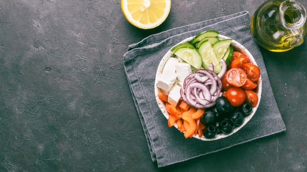 Greek Salad Bowl on dark black background, copy space. Above view of Bowl Greek Salad and ingredients. Trendy food. Idea, recept and concept of modern healthy food. Banner. Toned image.