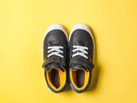 pair of new kids or adult sneakers on yellow background, top view. Flat lay gray and yellow or mustard color sneakers shoes on colorful bright background with copy space for text or design