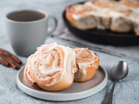 Vegan swedish cinnamon buns Kanelbullar with pumpkin spice,topping vegan cream cheese in plate with tea cup on table. Idea and recipe pastries - perfect cinnamon rolls. Copy space. Shallow DOF