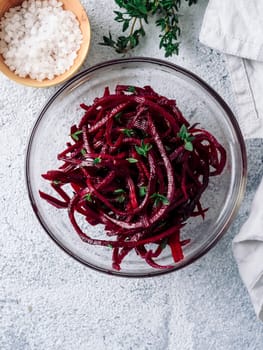 Raw beetroot noodles salad. Vegetable noodles - beet spaghetti on gray background. Copy space for text. Ideas and recipe for Clean eating, raw vegetarian food concept. Top view or flat lay. Vertical.