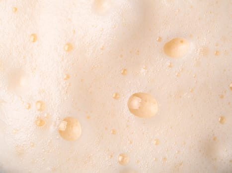 Foam texture extreme close up as background. Milkshake or cappucino foam with bubbles macro shoot. Copy space for text.