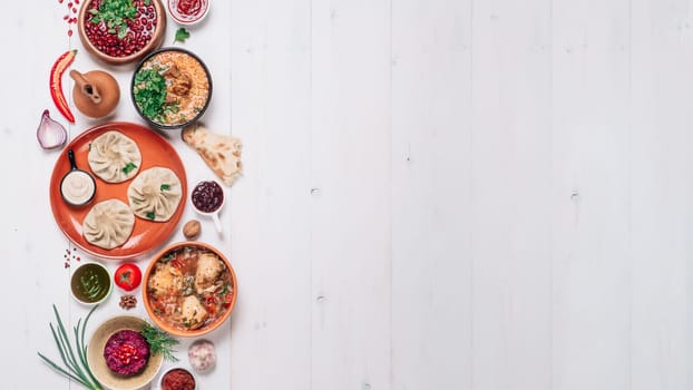 View from above of georgian cuisine on white wooden table. Banner traditional georgian food - khinkali, kharcho, chahokhbili, phali, lobio and local sauces. Top view. Copy space for text