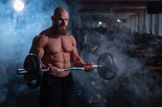 Caucasian bald topless man doing an exercise with a barbell in the gym. Bicep curls with weights