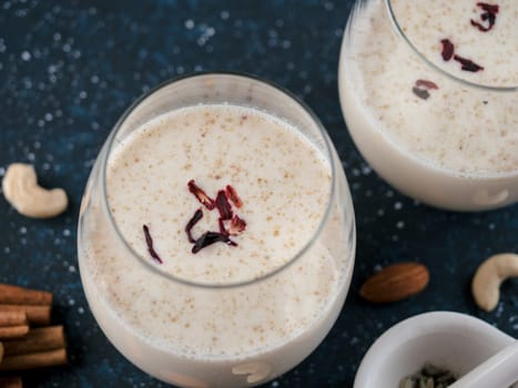 Thandai or Sardai cold drink made during Holi festival. Cold milk drink in glass, with ingredients - nuts and spices. Copy space