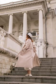 woman in elegant coat and hat against an intricate architectural backdrop, harmoniously blending modern fashion with historical allure. The soft daylight adds to its timeless appeal