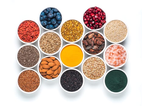 Various superfoods in smal bowl isolated on white background. Superfood as chia, spirulina, raw cocoa bean, goji, hemp, quinoa, bee pollen, black sesame, turmeric. Top view or flat-lay.