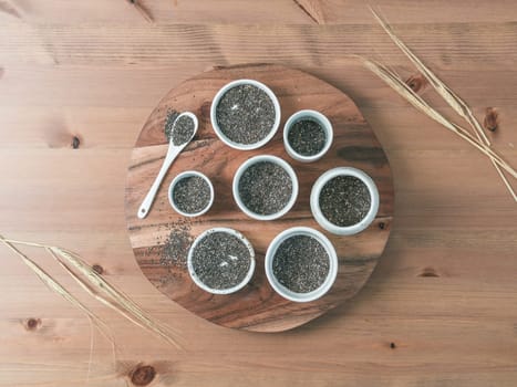 Organic chia seeds on wooden table. Set of small bowls with organic chia seed. Superfood concept. Copy space. Top view or flat-lay.