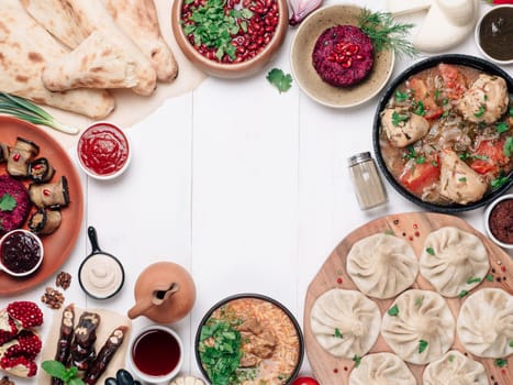 View from above of georgian cuisine on whitewooden table.Traditional georgian food-khinkali,kharcho,chahokhbili,phali,lobio and local sauces - tkemali, satsebeli, adzhika.Top view.Copy space for text