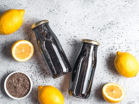 Detox activated charcoal black chia water or lemonade with lemon. Two bottle with black chia infused water. Detox drink idea and recipe. Vegan food and drink. Top view. Copy space for text.