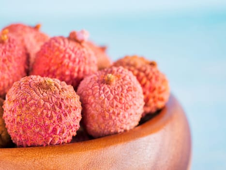 lychee fruit in clay plate on blue wooden background close up