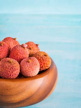 lychee fruit in clay plate on blue wooden background close up