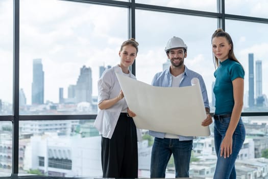 Group of smart architect engineer looking at camera while holding project plan. Skilled manager team discuss about building construction while standing near with city view. Team working. Tracery.