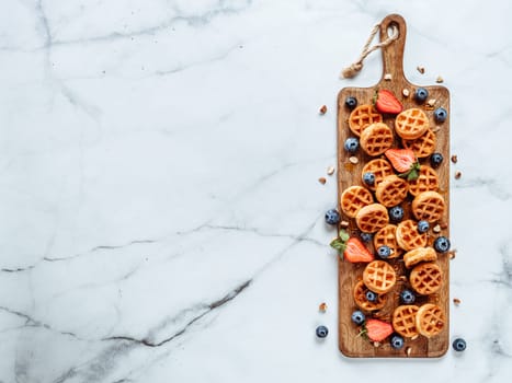 Small round delicious soft belgian waffles on cutting board. Fresh belgian waffles with berries and caramel sauce top view. Copy space for text or mock up