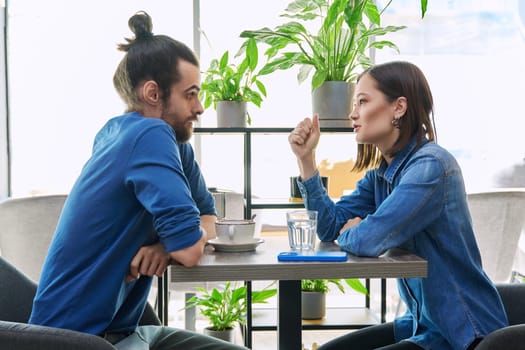 Young couple having serious conversation while sitting together in cafe. Relationships difficulties problems negative emotions lifestyle people concept