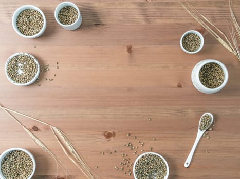 Hemp seeds in small white bowls and spoon on wooden table. Set of small bowls with raw organic unrefined hemp seed. Superfood and vegan concept. Top view or flat lay.Copy space for text