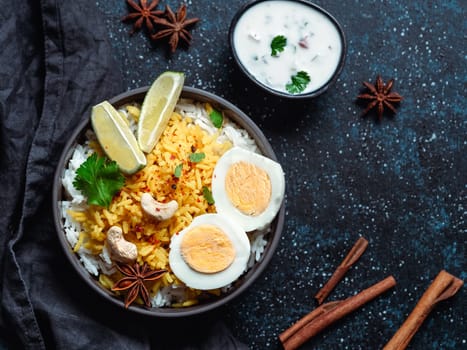 Indian Egg Biryani or anda rice top view on dark background. Egg Biryani - Basmati rice cooked with masala roasted eggs and spices, served with yogurt. Copy space for text