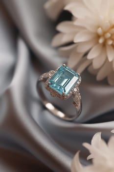 Elegant ring with emerald center stone and diamond accents surrounded by white flowers