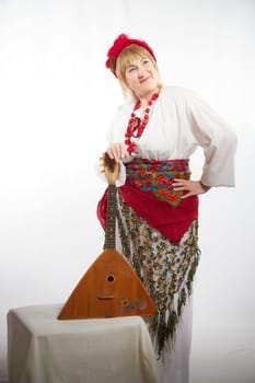 Cheerful funny adult mature woman solokha with musical balalaika. Female model in clothes of national ethnic Slavic style. Stylized Ukrainian, Belarusian or Russian woman poses in comic photo shoot