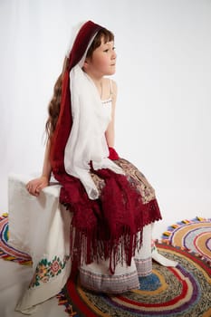 Portrait of Little girl in a stylized Tatar national costume on a white background in the studio. Photo shoot of funny young teenager who is not a professional model