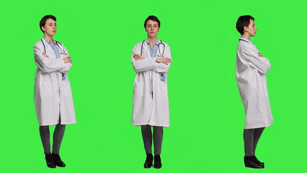 Woman medic posing with arms crossed in a white coat, feeling confident and successful with her medical career and expertise. Doctor having a stethoscope standing against greenscreen. Camera A.