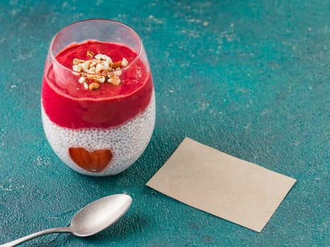 Idea for healthy breakfast on Valentine's Day: Chia pudding with red berry puree, chopped almonds on top and strawberry in the shape of heart. With blank valentines greeting card for text