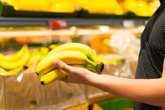 The person is holding a bunch of yellow bananas, a natural food that is both a delicious fruit and a nutritious ingredient commonly used in cuisine