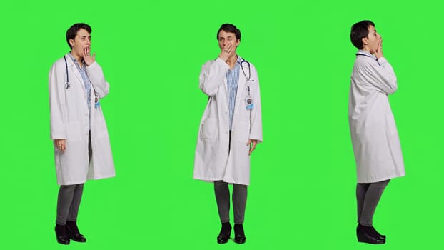 Tired general practitioner yawning and feeling overworked after night shift at hospital, exhaustion and work pressure. Medic being tired and experiencing burnout against greenscreen. Camera A.
