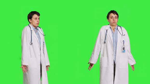 Physician being uncertain about something in studio, shrugging and feeling clueless about the right answer. Doctor doing i dont know symbol against greenscreen backdrop, confusion. Camera B.