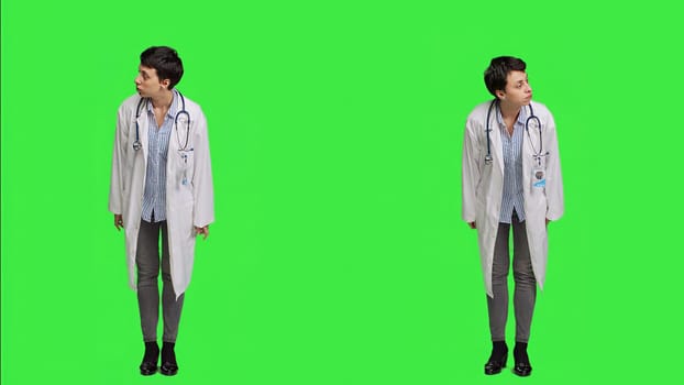 Woman physician looking around for patients to come at checkup exams, waiting for someone standing against greenscreen backdrop. General practitioner with white coat feeling impatient. Camera A.