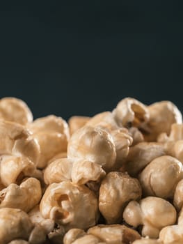 Close up view of caramel corn on black background. Vertical. Copy space.