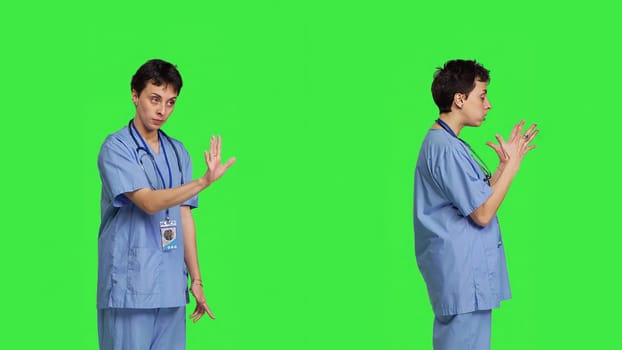 Displeased irritated nurse shouting no and arguing with someone against greenscreen backdrop, showing rage and anger while she wears hospital scrubs. Aggressive medical assistant. Camera B.