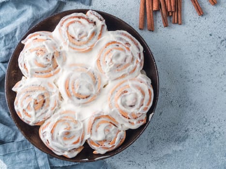 Idea and recipe pastries - perfect cinnamon rolls with topping, top view in skillet. Vegan swedish cinnamon buns Kanelbullar with pumpkin spice,topping vegan cream cheese.Flat lay. Copy space for text